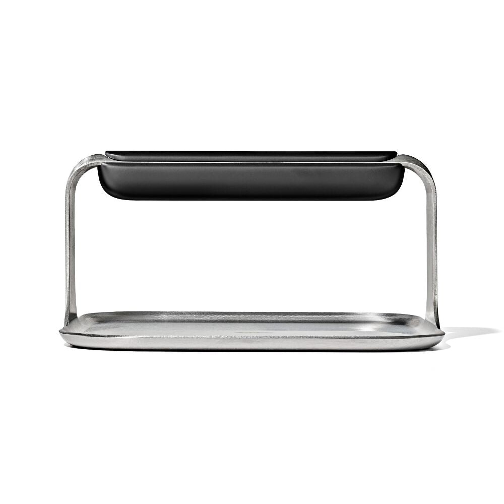 Side view of a metal griddle press with a black handle. 