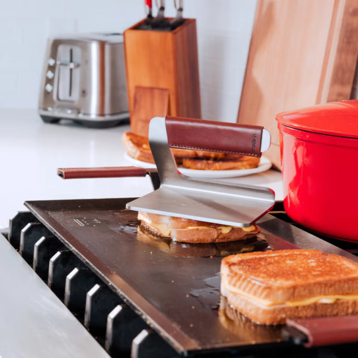 Grilled sandwiches on a hotplate with kitchen items in the background