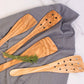 Set of wooden cooking utensils on a gray cloth with a white background