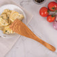 Wooden spoon serving pasta with vegetables on a marble surface