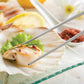 Scallops on a plate with lemon and herbs, served with chopsticks.