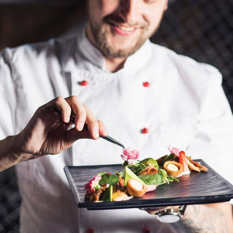 Chef holding a plate of food with a blurred background