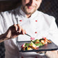 Chef holding a plate of food with a blurred background