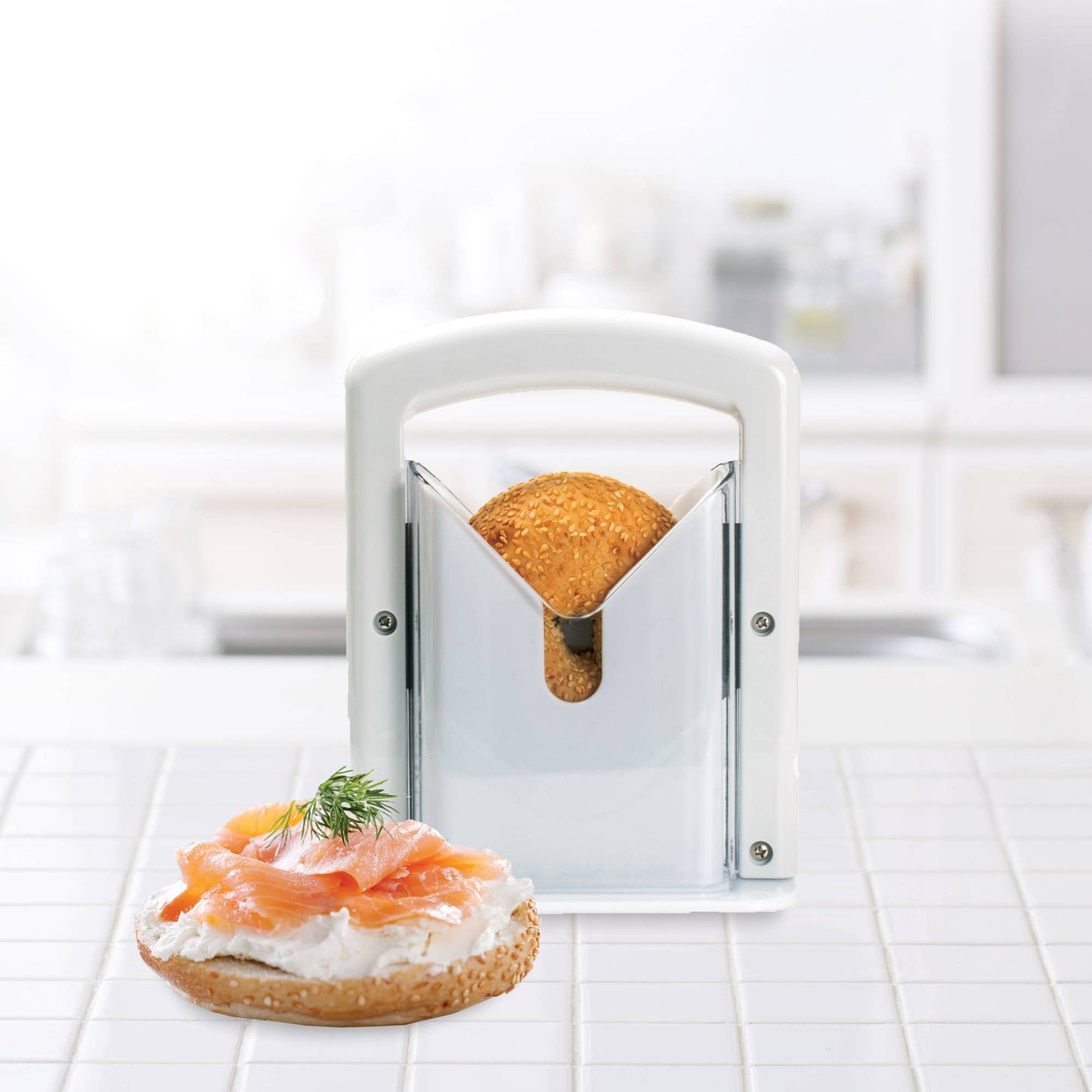 Bread with cream cheese and salmon on a white surface, with a bread slicer in the foreground.