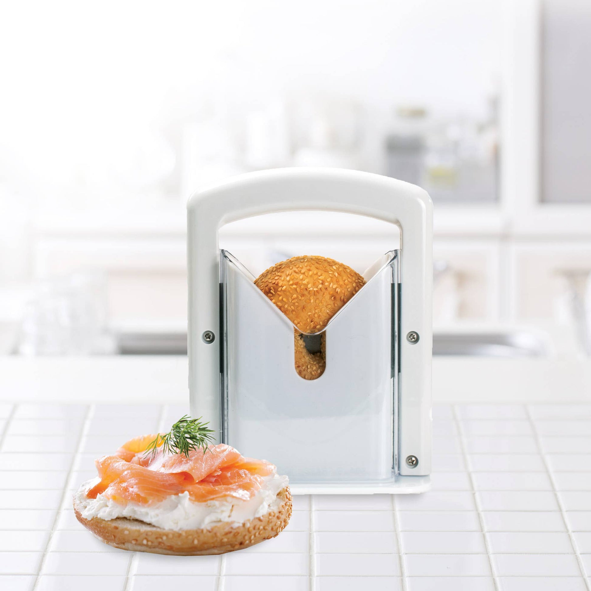 Bread with cream cheese and salmon on a white surface, with a bread slicer in the foreground.