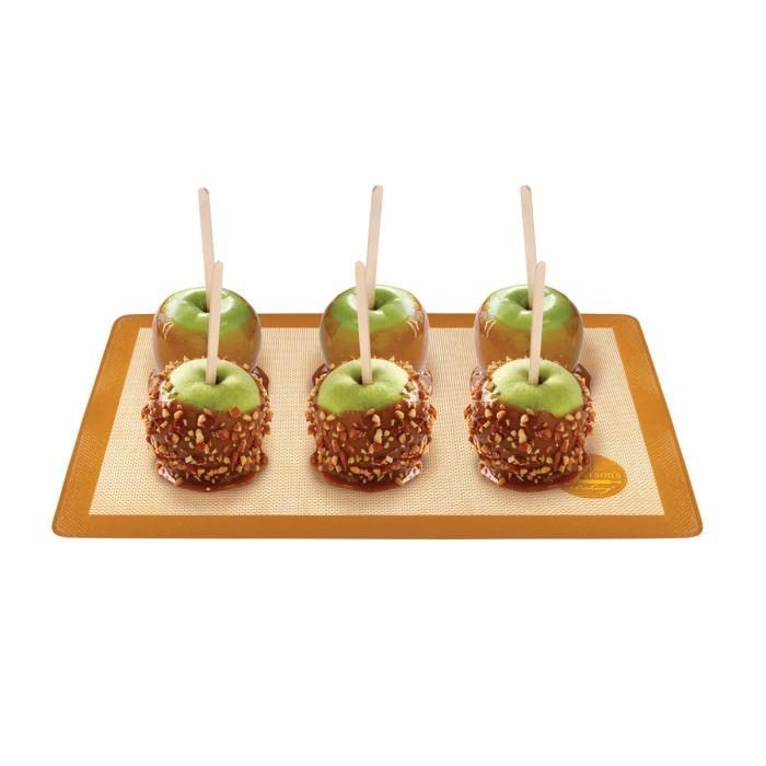Brown baking mat with candied apples and a white background