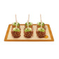 Four caramel apples on a wooden board with a white background