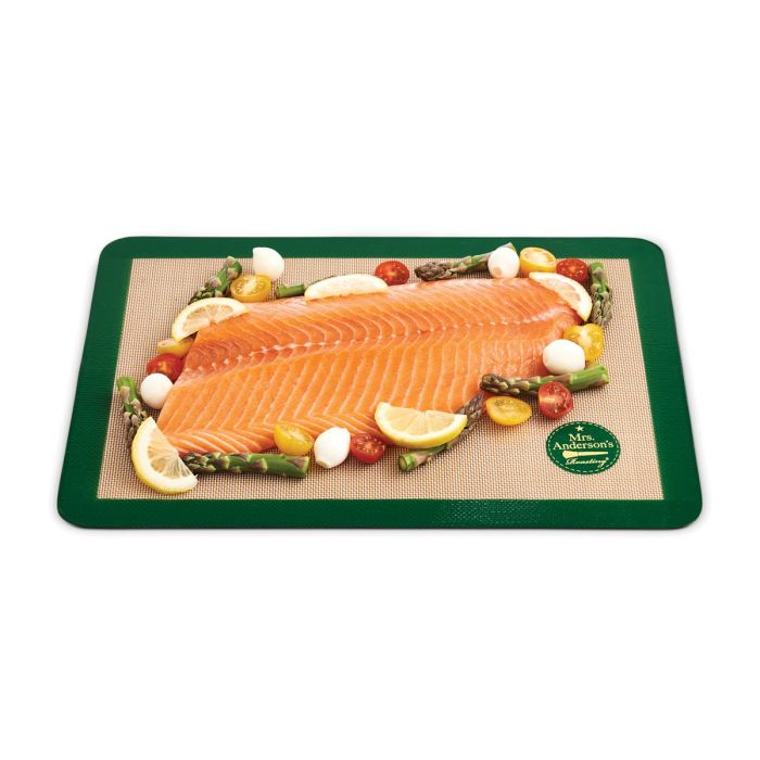 Raw salmon fillet on a silicone baking mat with vegetables on a white background