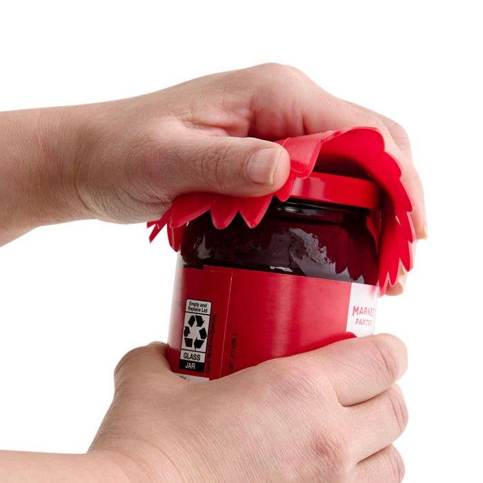 Person using a red jar opener on a glass jar with a white background