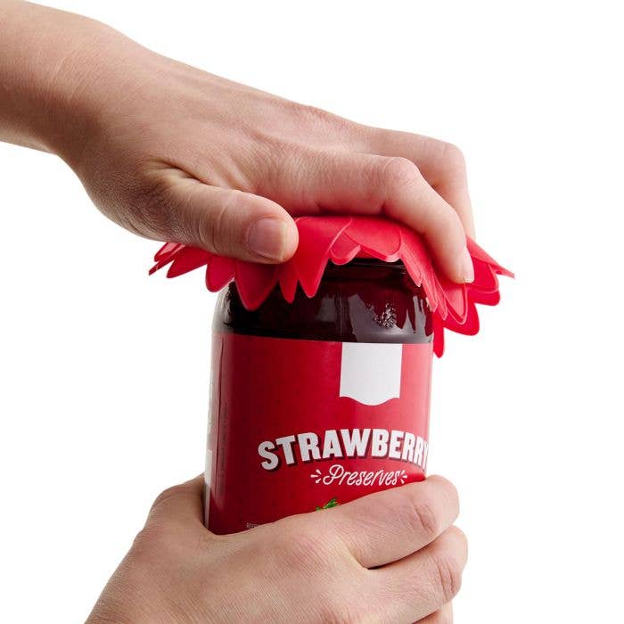 Person using a red strawberry preserve lid crimper on a jar.