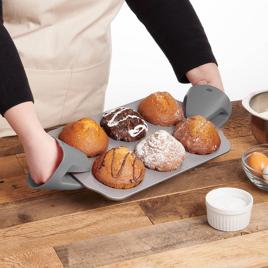 Person holding a tray of freshly baked pastries on a wooden surface