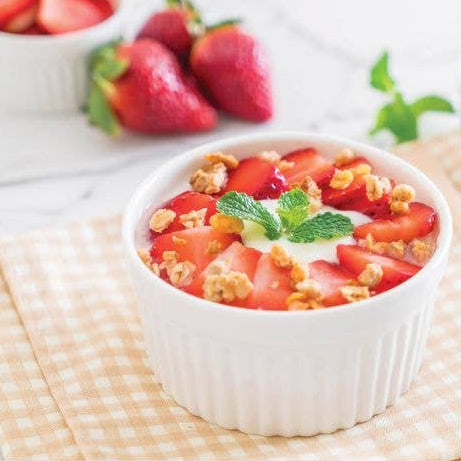 Yogurt bowl with strawberries and granola on a checkered cloth