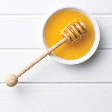 Jar with honey and a wooden dipper on a white background