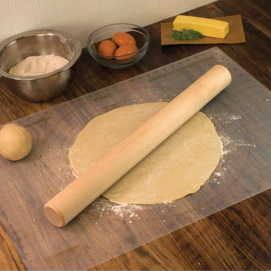 Rolling pin on rolled-out dough with ingredients in the background on a wooden surface.