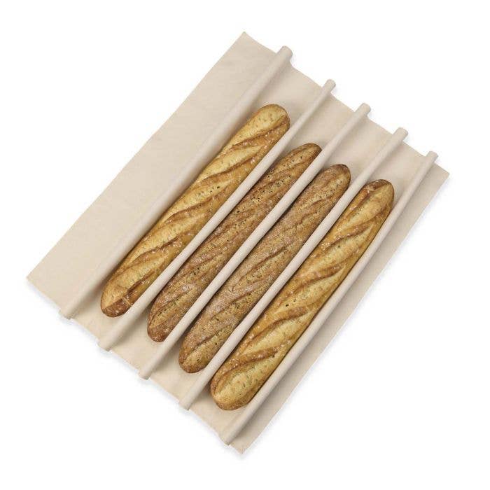 Four baguettes in a beige bread holder on a white background