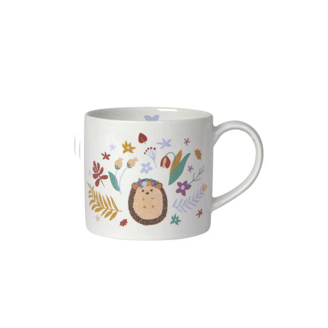  "Hedge Hugs" Mug in a Box brings a cozy, nature-inspired charm to your mornings. Featuring a whimsical hedgehog surrounded by wildflowers and a smooth white interior, 