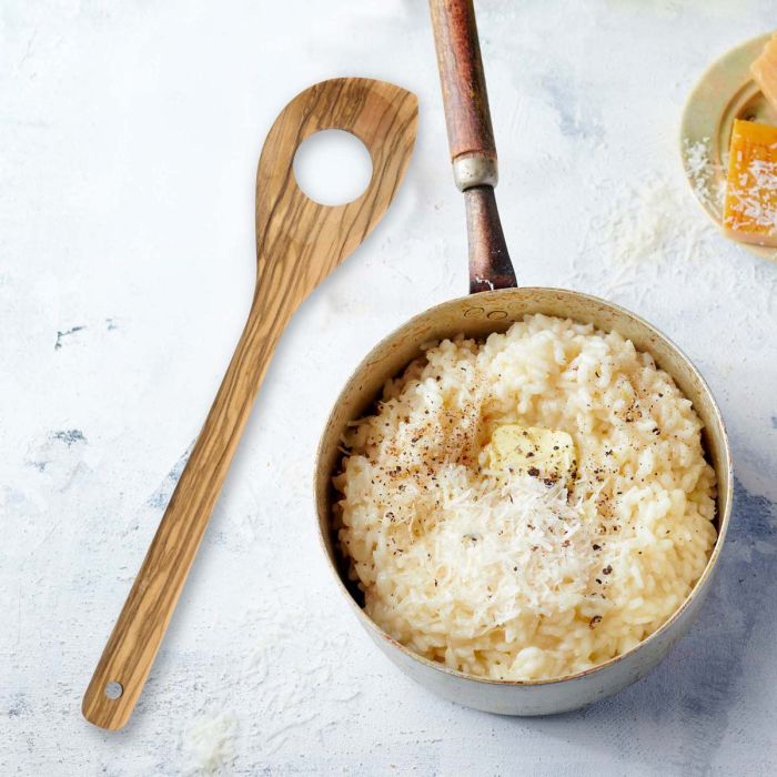 Bowl of creamy risotto with a wooden spoon on a light background