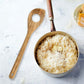Bowl of creamy risotto with a wooden spoon on a light background