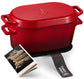 Red cast iron Dutch oven with a recipe book and towel on a white background