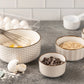 Set of ceramic bowls with kitchen items on a countertop