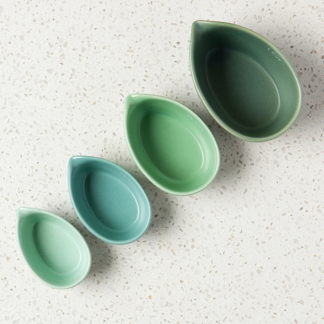 Stoneware set of 4 measuring cups that comes in a giftable box! Comes with 1/4 cup, 1/3 cup, 1/2 cup, and 1 cup green ombre stoneware measuring cups.