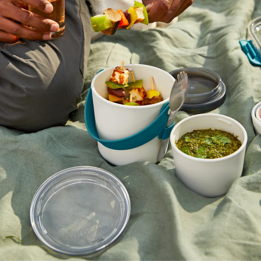 Lunch pot open on blanket with food being eaten