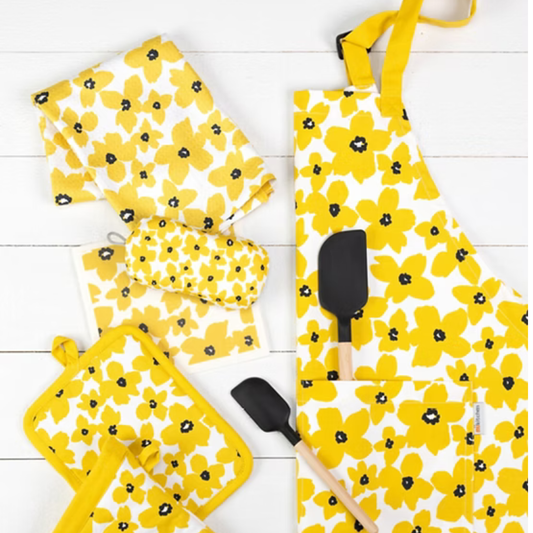Yellow floral apron with matching oven mitts and pot holders on a white wooden surface.