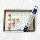 Baking sheet with macaron silicone mold and colorful macaron shells on a white surface