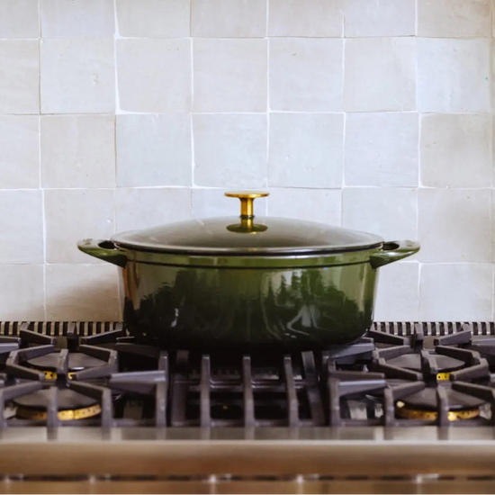 Green pot on a gas stove with tiled wall in the background
