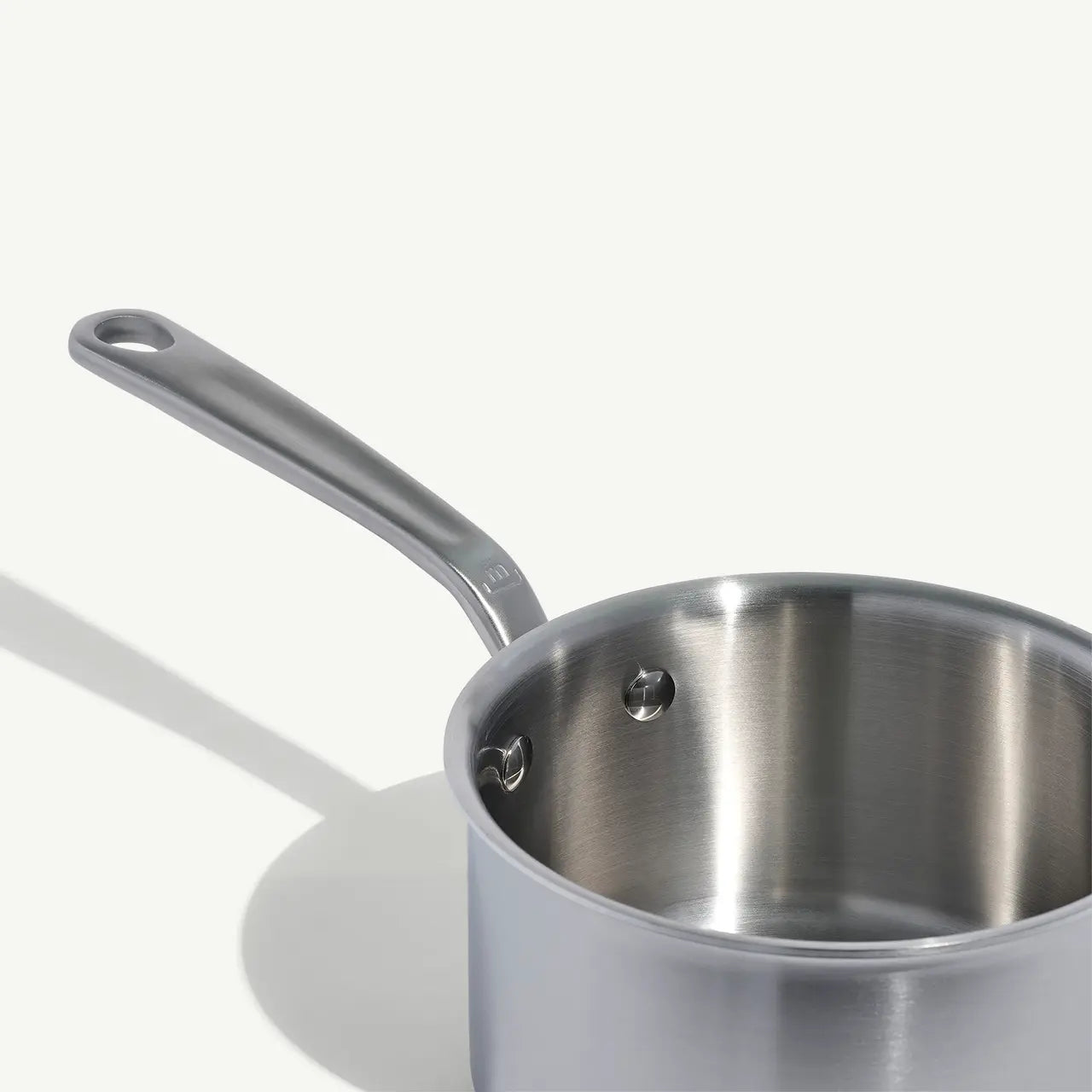 A stainless steel saucepan with a long handle, set against a white background.