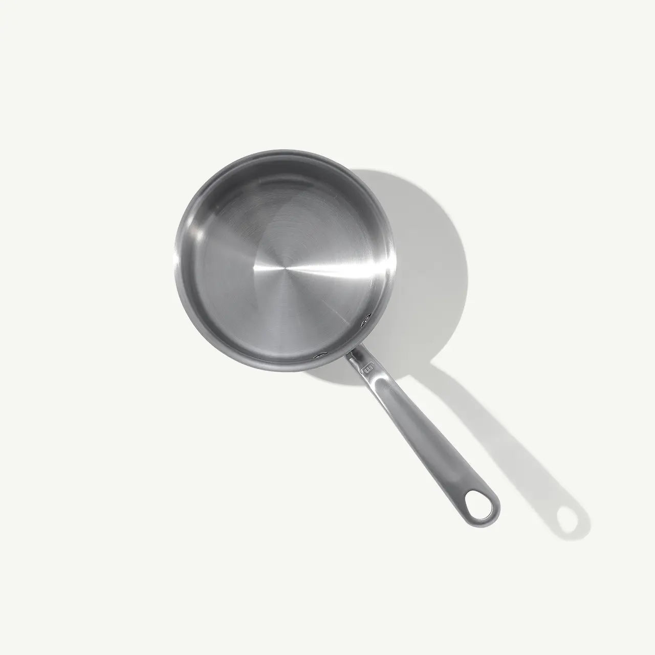 A stainless steel saucepan with a long handle, set against a white background.