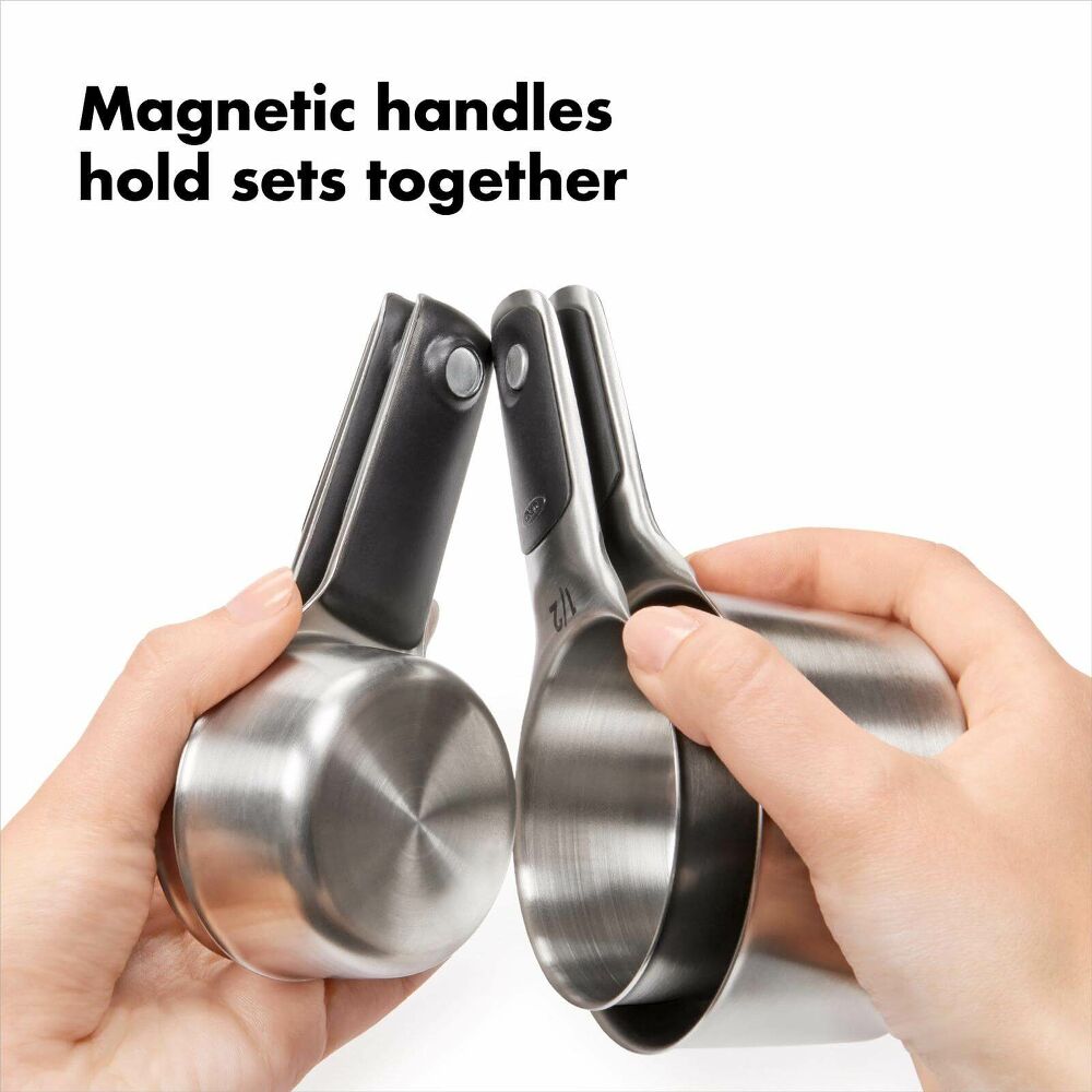 Hands holding a set of 4 silver magnetic measuring cups 