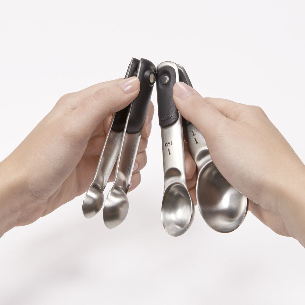 Hands holding 4 magnetic measuring spoons. 
