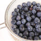 Blueberries in a metal strainer on a white background