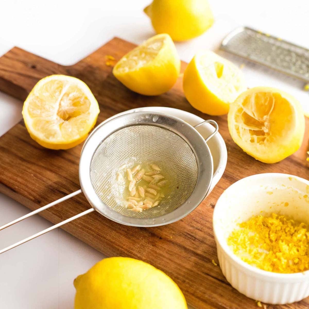 Strainer with lemon seeds, lemons on a cutting board