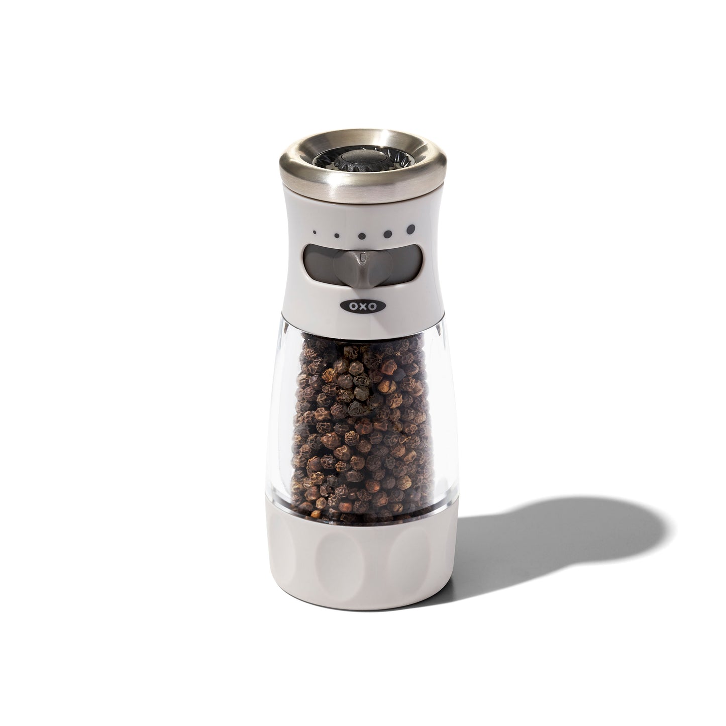OXO pepper grinder with black peppercorns on a white background