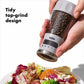 Hand using pepper grinder with tidy top grind design.