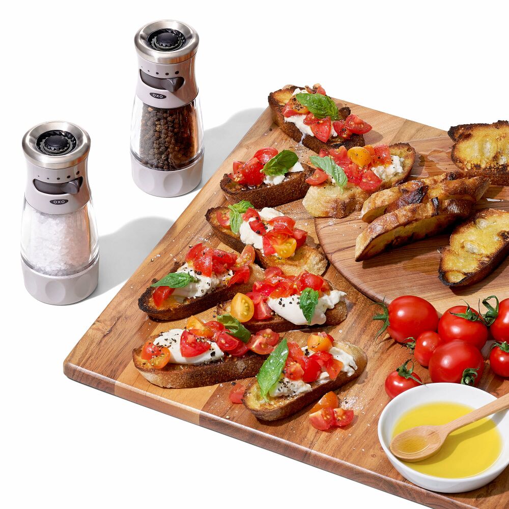 Salt and pepper grinders with cutting board and tomatoes on toast. 