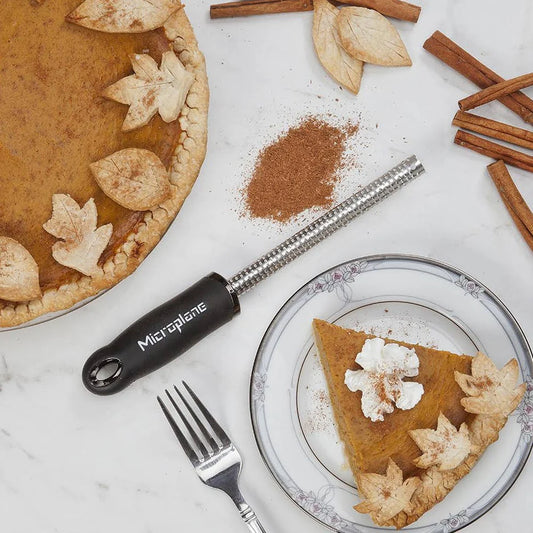 Spice grater on  table with pumpkin pie and cinnamon