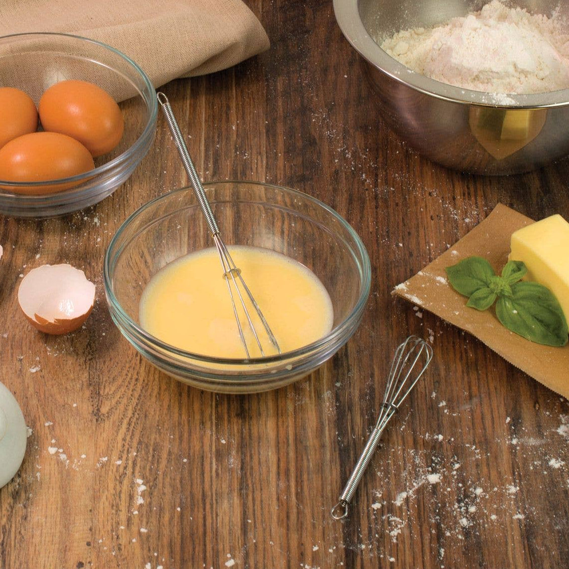 Bowl of whisked eggs with a wooden background, including eggs and butter.