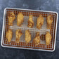 Baked chicken wings on a cooling rack and served with sauce on a black plate.