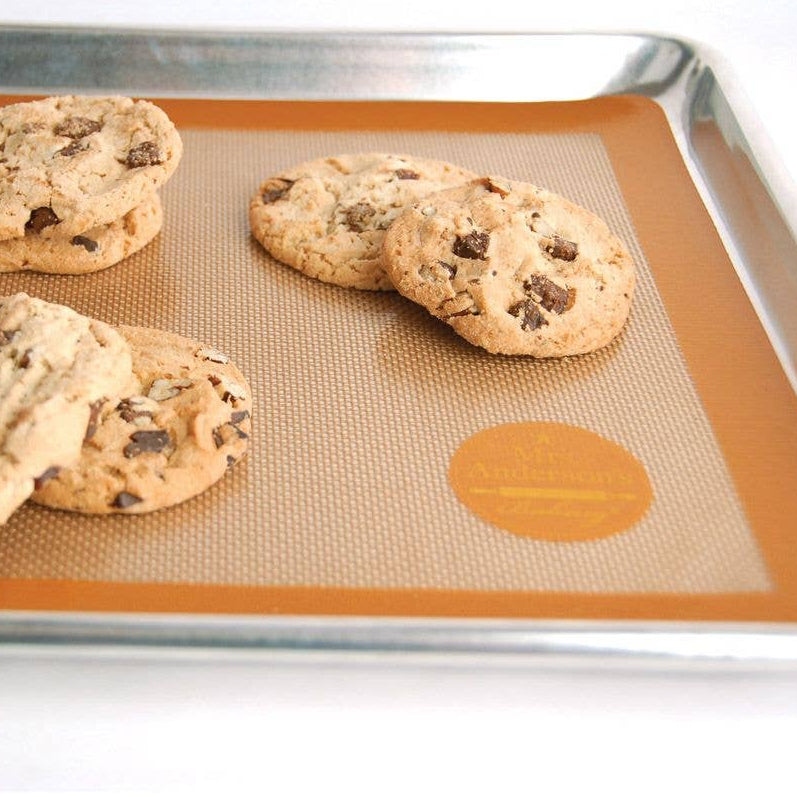 Chocolate chip cookies on a silicone baking mat with a brand logo.