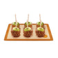 Four caramel apples on a wooden tray with a white background