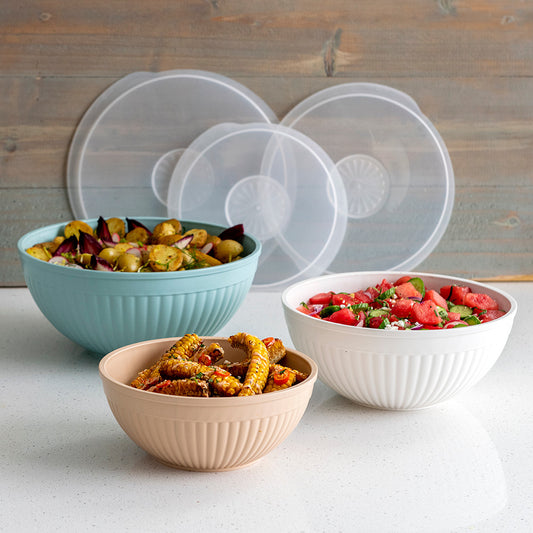 Three bowls with different food contents on a light surface with clear lids in the background.