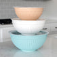 Three stacked mixing bowls in beige, white, and light blue on a kitchen counter.