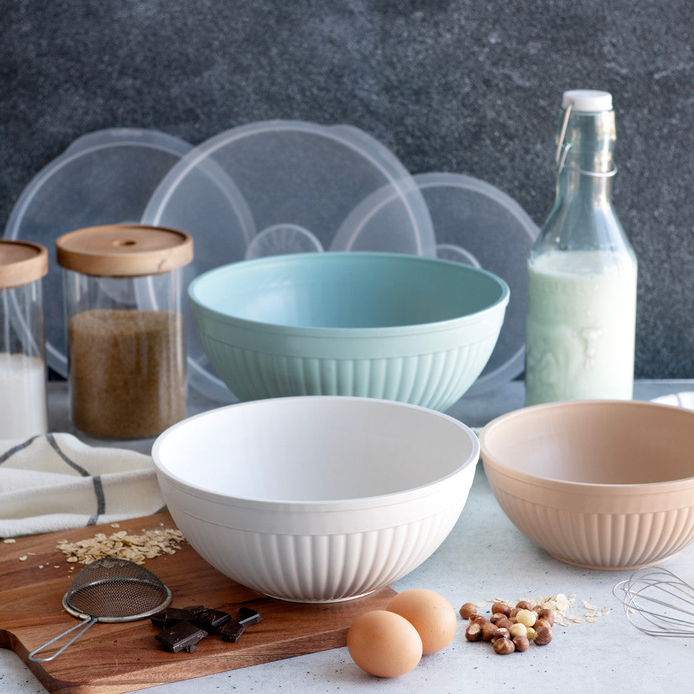 Set of bowls on a kitchen counter with ingredients and a bottle of milk.