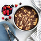 Marbled cake in a white dish with berries and a blue plate on a white surface