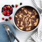 Marbled cake in a white dish with berries and a blue plate on a white surface