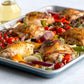 Roasted chicken with vegetables on a white plate with a glass of white wine in the background.