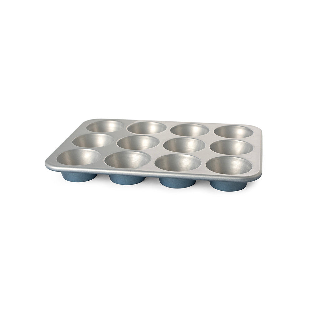 Metal muffin tin with blue silicone cups on a white background